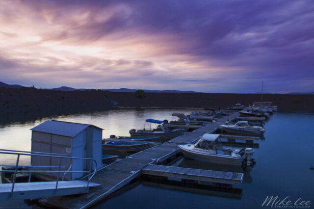 Evening photograph of the Gallatin Marina at Eagle Lake in Lassen County, Northern California, captured during the summer of 2006. The calm waters reflect the soft lavender and golden tones of the setting sun as boats rest quietly in their slips — a tranquil moment from what truly were “better days” for the lake. Once a thriving hub for anglers and boaters, the marina has since fallen dry due to years of drought, leaving behind only grass and memories where water once shimmered. Still, Eagle Lake endures — and with the return of wet winters and replenished snowpack, there’s hope that scenes like this will grace its shores again.