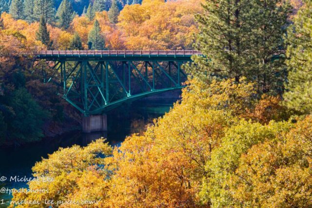 Lake Britton Bridge Autumn The Highway 89 bridge crossing Lake Britton in Shasta County, Northern California, surrounded by brilliant autumn foliage. The green steel structure contrasts with the warm tones of the surrounding forest, viewed from near the historic rail bridge featured in the movie *Stand By Me*.