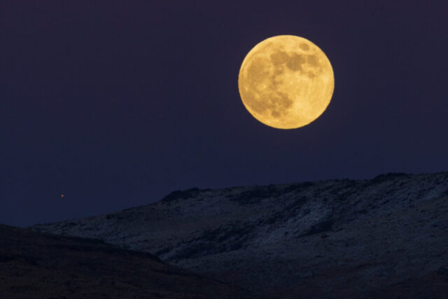 20221207_Moon_and_Marse_Social__001 Telephoto image of the full moon and Mars rising together above the Skedaddle Range in Lassen County, California. The photograph captures the warm golden glow of the moon as it ascends into a deep twilight sky, its surface rich with visible craters and maria. Below, the rugged slopes of the Skedaddle Range are dusted with snow, their subtle textures illuminated by the fading dusk light. Just to the lower left of the moon, the bright reddish point of Mars adds a striking celestial accent, symbolizing the rare and beautiful alignment of Earth