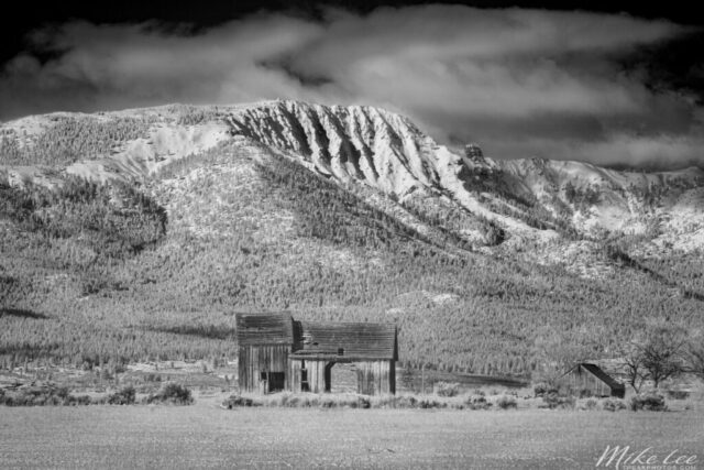 The Barn and Thompson Peak A dramatic black and white infrared photograph of an old weathered barn set beneath snow-covered Thompson Peak in Lassen County, California. Captured with an 830nm infrared filter that blocks visible light, the image reveals striking contrast between the bright white clouds and the deep, nearly black infrared-rendered sky. Fresh snow from a recent storm highlights the rugged textures of the Sierra Nevada foothills, while the aged barn in the foreground adds a timeless rural character. This high-contrast infrared composition transforms a familiar winter landscape into a hauntingly beautiful vision of mountain solitude and quiet resilience.