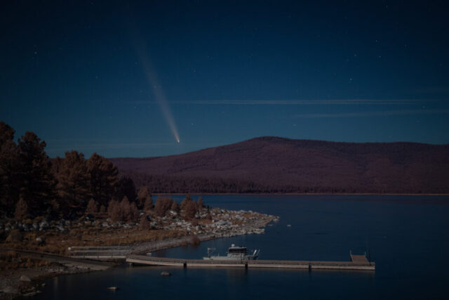 Eagle and Atlas Nighttime photograph of comet C/2023 A3 Tsuchinshan-ATLAS seen over Eagle Lake in Lassen County, California, captured from the breakwater at the Gallatin Marina on October 14, 2024. Taken during nautical twilight under an 85% moon, the long-exposure image reveals the comet’s brilliant nucleus and dramatically long tail stretching high above the dark silhouette of the surrounding hills. The moonlight bathes the lake, marina, and Lassen County Sheriff’s patrol boat in a soft silvery glow, highlighting the rocky shoreline and pine trees. Shot at roughly 50mm on a full-frame camera with an 8-second exposure, this astrophotography composition conveys both the technical precision and natural beauty of observing a rare celestial event from one of Northern California’s serene alpine lakes.
