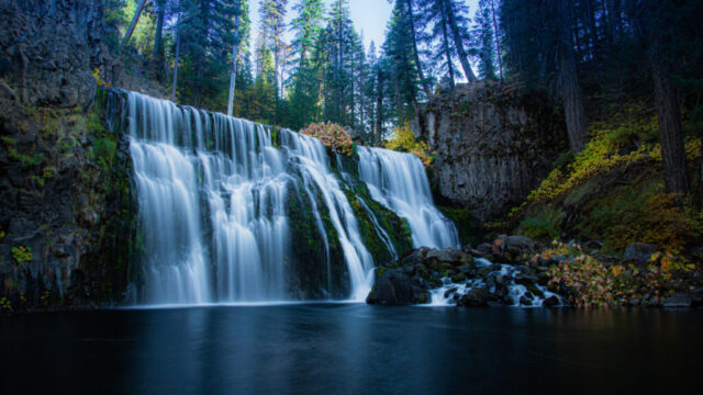 McCloud Middle Falls Autumn Evening Evening photograph of McCloud Middle Falls on the McCloud River in Northern California, captured in late October as soft twilight settled over the canyon. This long exposure image highlights the silky, flowing texture of the waterfall as it cascades gracefully over dark volcanic rock into a calm reflective pool below. The surrounding autumn foliage adds warm tones of gold and amber, contrasting beautifully with the cool blues of the shaded water and basalt cliffs. Taken from the base near Fowler’s Campground, this fine art landscape conveys the peaceful solitude and natural majesty of one of California’s most beloved waterfalls.