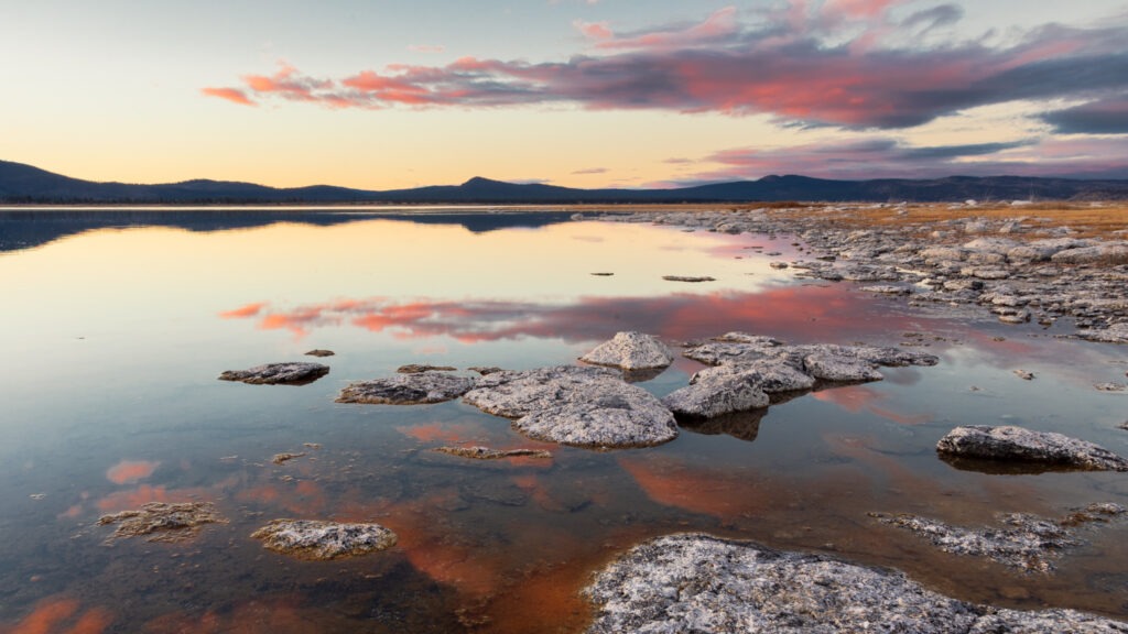 Rocky shoreline at Miner’s Point on the eastern shore of Eagle Lake, showing calm dusk reflections of pastel clouds and distant ridges while looking north on a December evening.