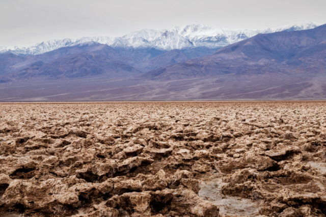 Jagged halite salt formations at Devil's Golf Course, Death Valley National Park, with snow-capped Panamint Range beyond