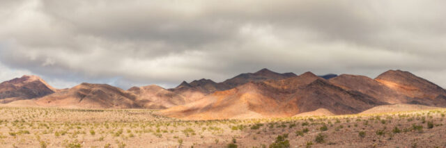 Dappled light on desert ridgelines under stormy clouds along Daylight Pass Road, Death Valley National Park, California, January