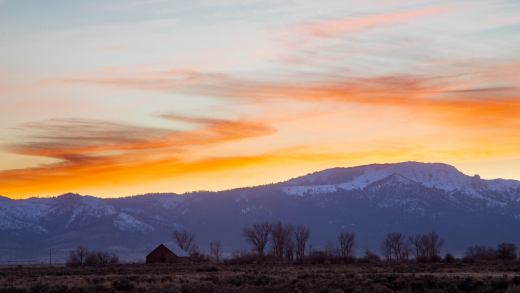 Thompson Peak rises above winter ranchland at sunset in Lassen County, California, just after the sun drops below the ridgeline.