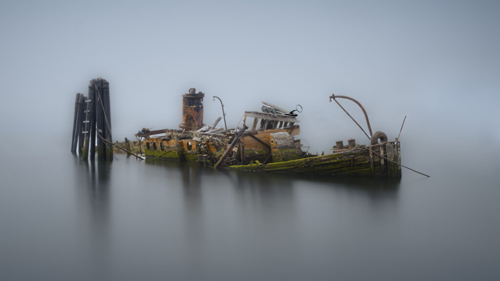 Wreck of the Mary B. Hume, an 1881 steam vessel slowly decaying at the Gold Beach, Oregon waterfront amid dense coastal fog
