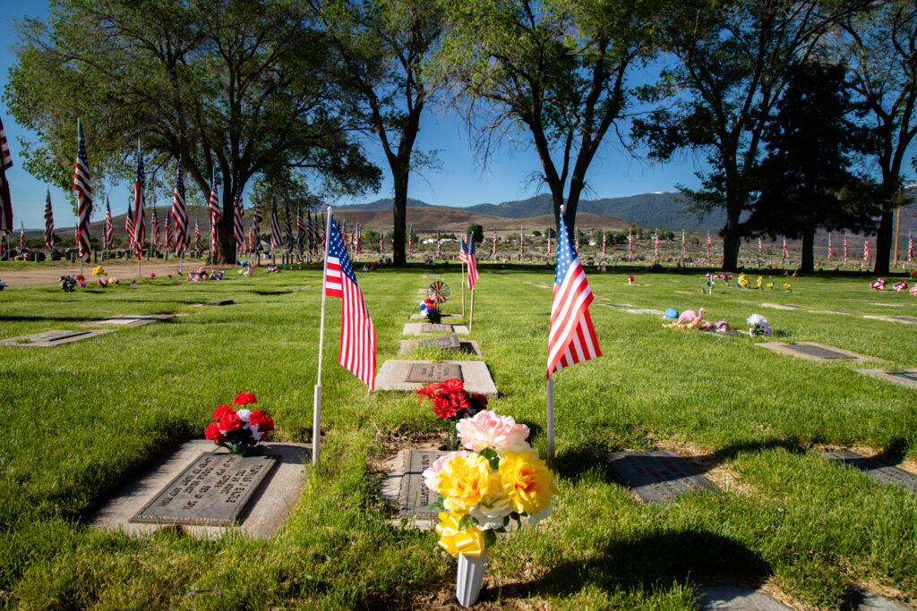 American flags and fresh flowers mark a grave at Diamond Crest Cemetery, Johnstonville CA, on Memorial Day